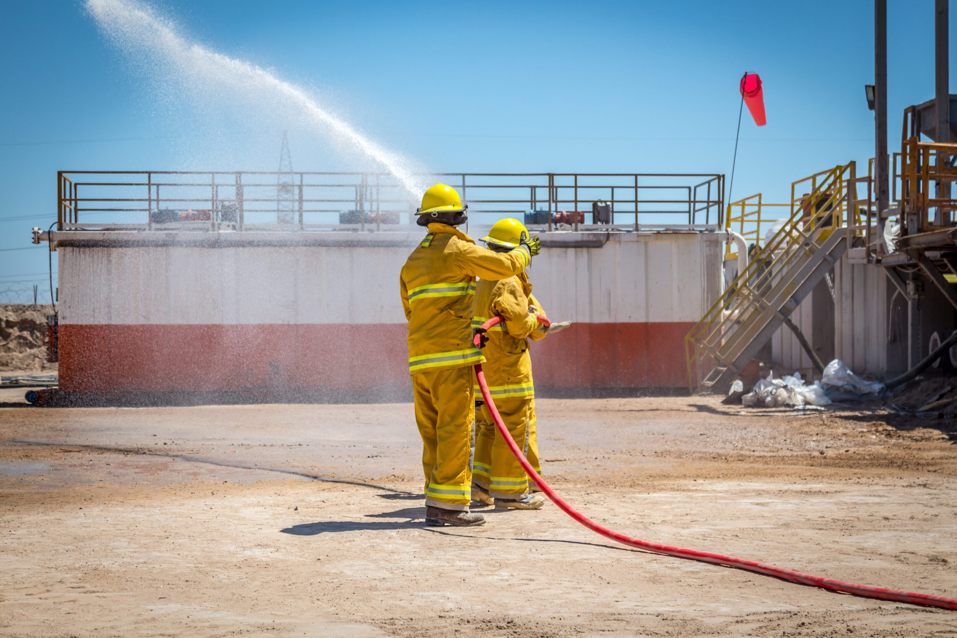 Firefighters spraying water at industrial site.
